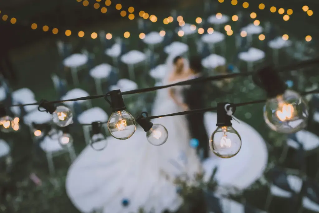 Guirnaldas de bombillas iluminando el montaje de una boda al anochecer