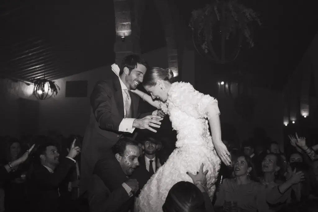 Los novios a hombros en plena pista, rodeados de invitados