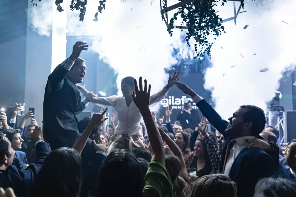 Pista de baile llena con humo, confeti y la pantalla de Gilafest al fondo