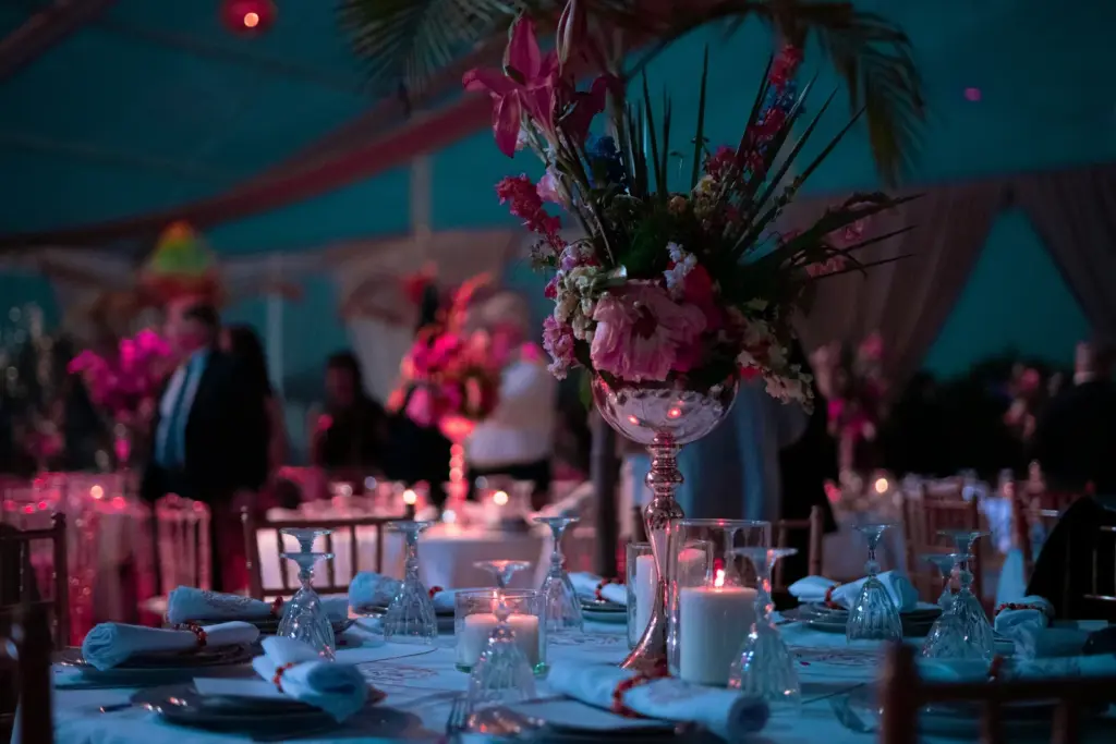 Mesa vestida con copas, velas y un centro floral alto en copa de plata