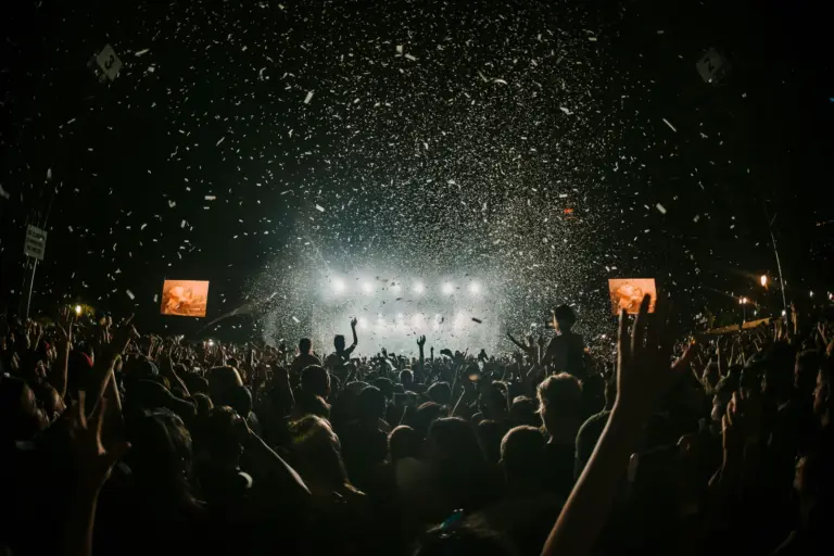 Público con las manos en alto ante el escenario de un festival entre confeti
