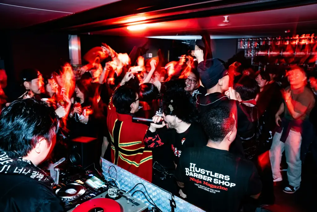 Pista de baile llena en una fiesta privada con iluminación roja y DJ