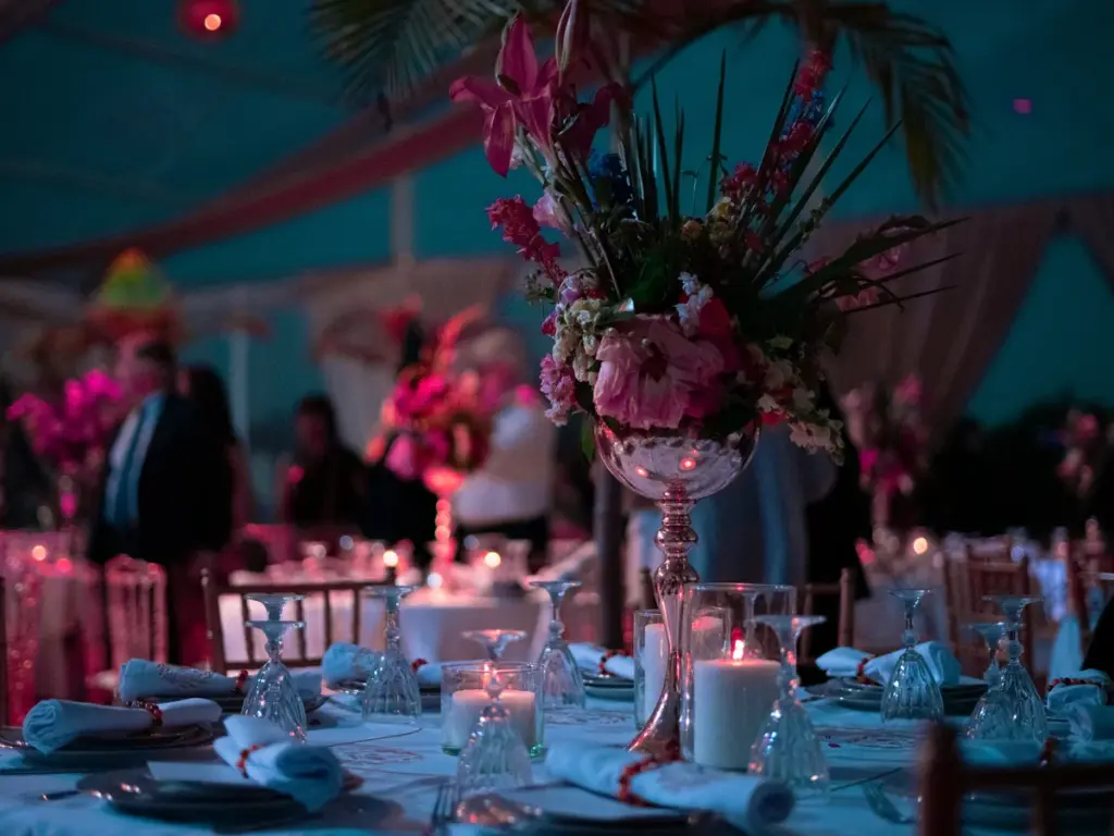 Mesa decorada con flores y velas bajo iluminación de color en la fiesta de fin de año