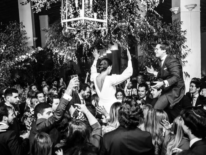 Novia bailando rodeada de invitados durante una boda, en blanco y negro.